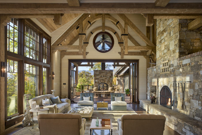 Interior, horizontal, living room toward looking out to covered patio with fireplace, Bowden residence, Balsam Mountain Preserve, North Carolina; M. Shawn Leatherwood & Associates; Morgan Keefe Builders