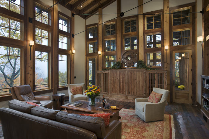 Interior, horizontal, living room toward entertainment center and screened porch looking out windows to fall color, Parker residence, Balsam, North Carolina; M. Shawn Leatherwood & Associates; Barber Builders; Harmony Timberworks