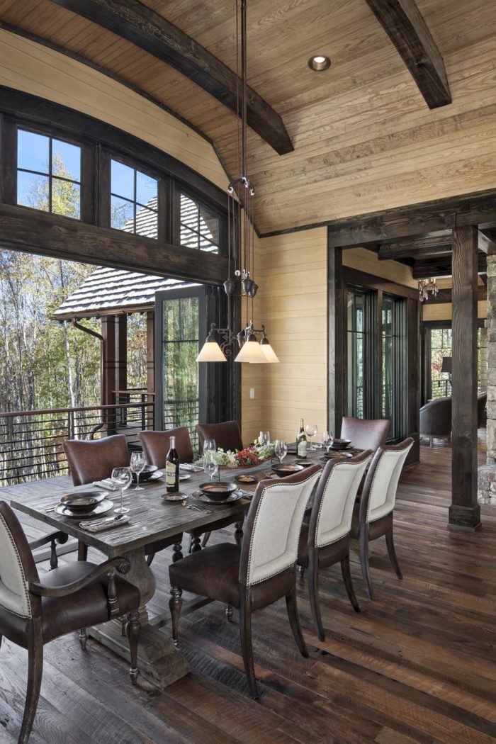 Interior, vertical, dining room looking into living room and out bifold doors to deck, Lemonine residence, Balsam Mountain Preserve, North Carolina; M. Shawn Leatherwood & Associates; Morgan-Keefe Builders